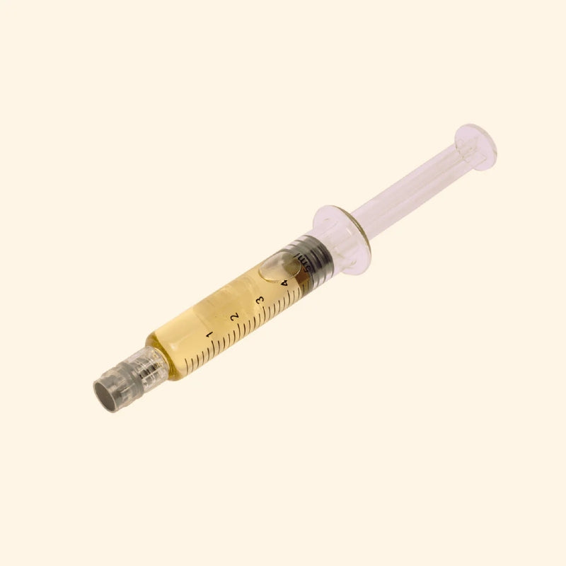 Medical Cannabis Extract syringe with a clear cartridge on a beige background