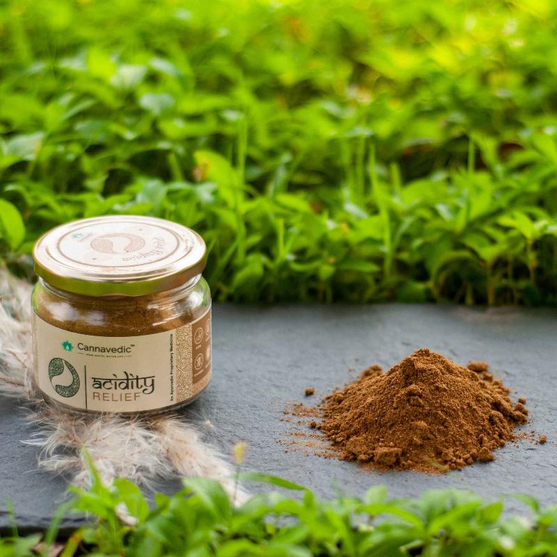 Jar labeled "Acidity Relief" by Cannavedic next to a small pile of brown powder, set against a green background.