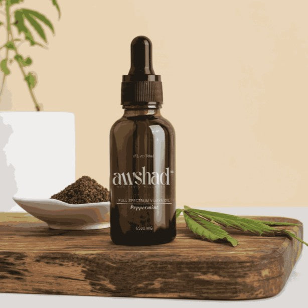 Brown bottle with dropper labeled 'awshad' on a wooden surface with cannabis leaves and seeds.