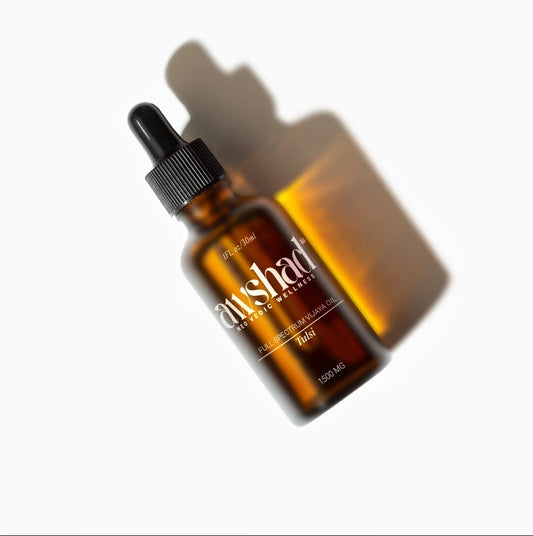 Amber glass awshad CBD Oil bottle with label on a white background, casting a shadow.