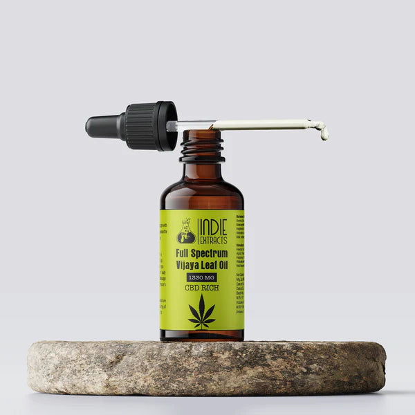Bottle of Indie Extracts Full Spectrum Vijaya Leaf Oil on a stone surface with a white background