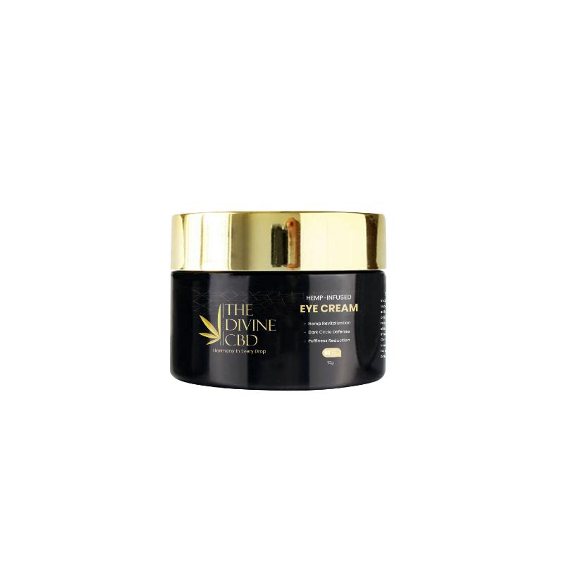 A jar of "THE DIVINE CBD" hemp-infused eye cream with a black body and gold lid.