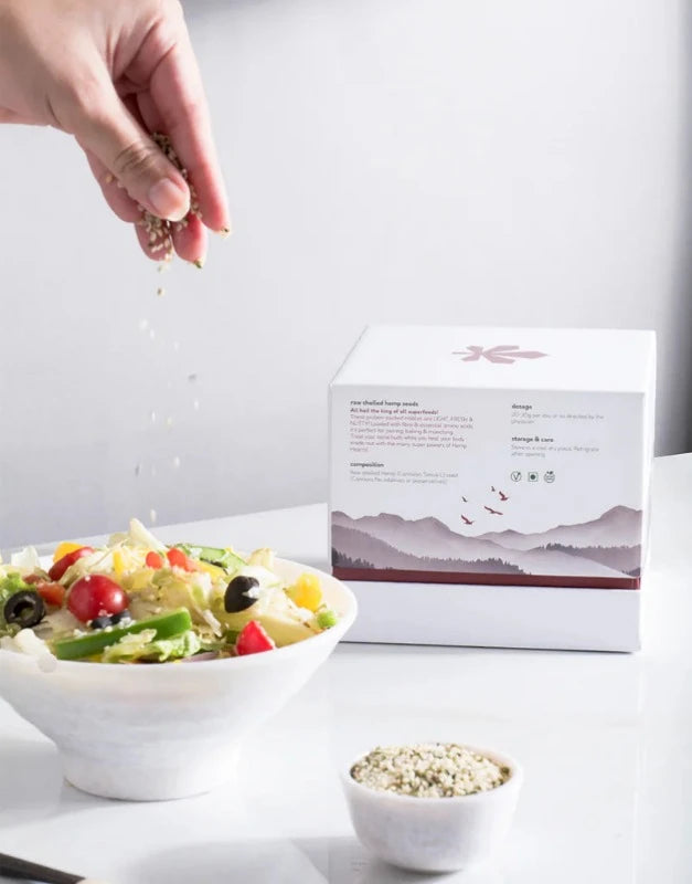 a bowl of salad next to a box of hemp hearts.