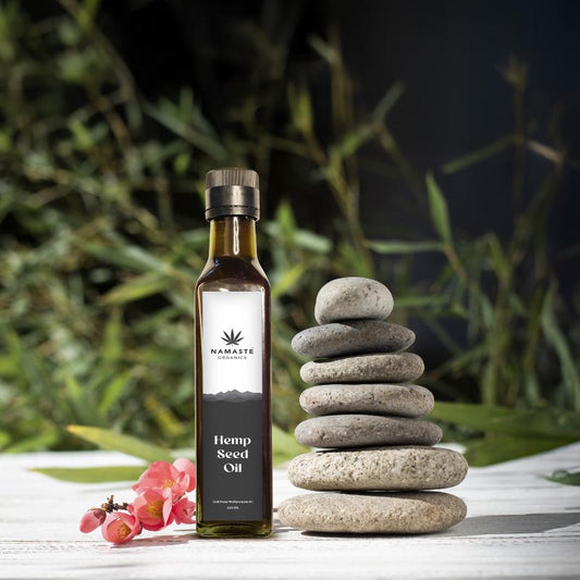 Bottle of Namaste Organics Hemp Seed Oil with stacked stones and flowers on a natural background