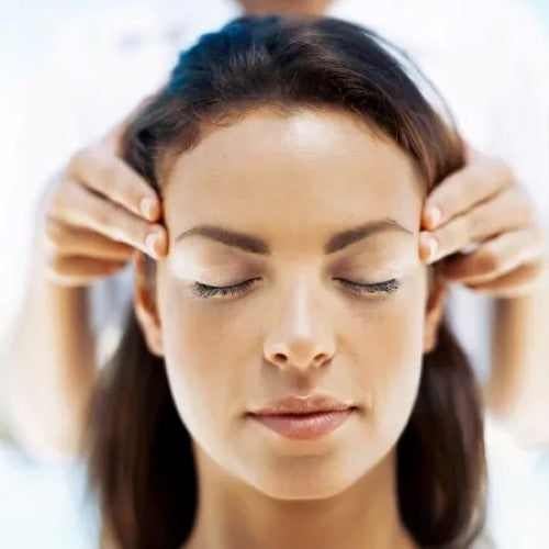 A woman with eyes closed, holding her temples in distress.