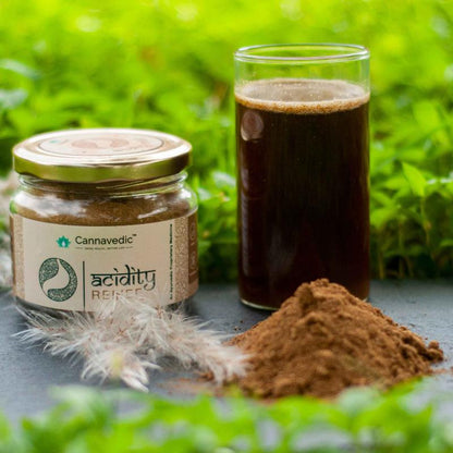 A jar labeled "Cannavedic acidity RELIEF" and a small pile of brown powder on a dark surface with green foliage in the background.