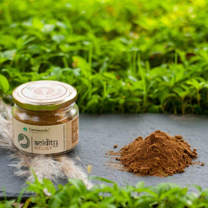 Jar labeled "Acidity Relief" by Cannavedic next to a small pile of brown powder, set against a green background.