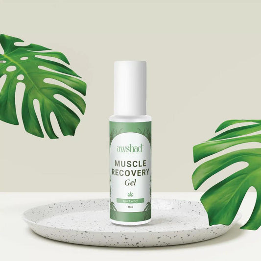 Awshad CBD Muscle recovery gel bottle on a speckled plate with tropical leaves in the background.