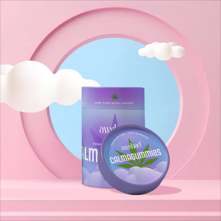 Purple and blue container contains cannabis cbd thc gummies with lid against a pink background with clouds.
