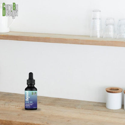 Cure By Design CBD oil bottle on a wooden surface with a white wall background