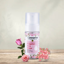 Load image into Gallery viewer, Cannarma Rose Water Oil spray bottle on wood, surrounded by pink roses. For all skin types, with vitamin C.
