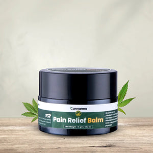 Cannarma Pain Relief Balm container on a wooden surface with leaves in the background.