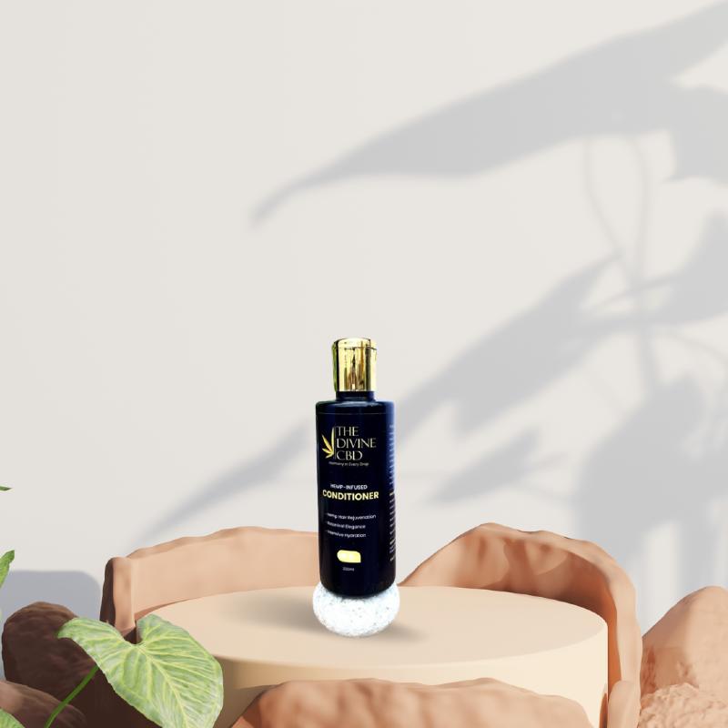 Blue bottle of hemp-infused conditioner with a gold cap on a beige platform, surrounded by earthy-toned stones and plant shadows in the background.

