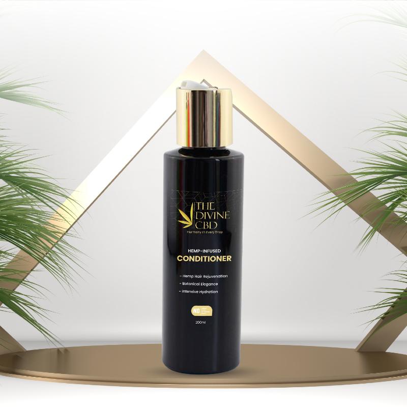 Black bottle of "The Divine CBD" Hemp-Infused Conditioner with gold cap and branding. Palm leaves and gold geometric design in the background.