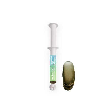 White syringe with brown color cannabis leaf extract and a blob of the same substance.