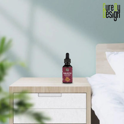 Bottle of Manjistha on a nightstand with a blurred bedroom background