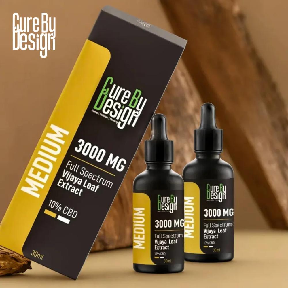 Cure By Design CBD products including a box and two bottles on a wooden surface.