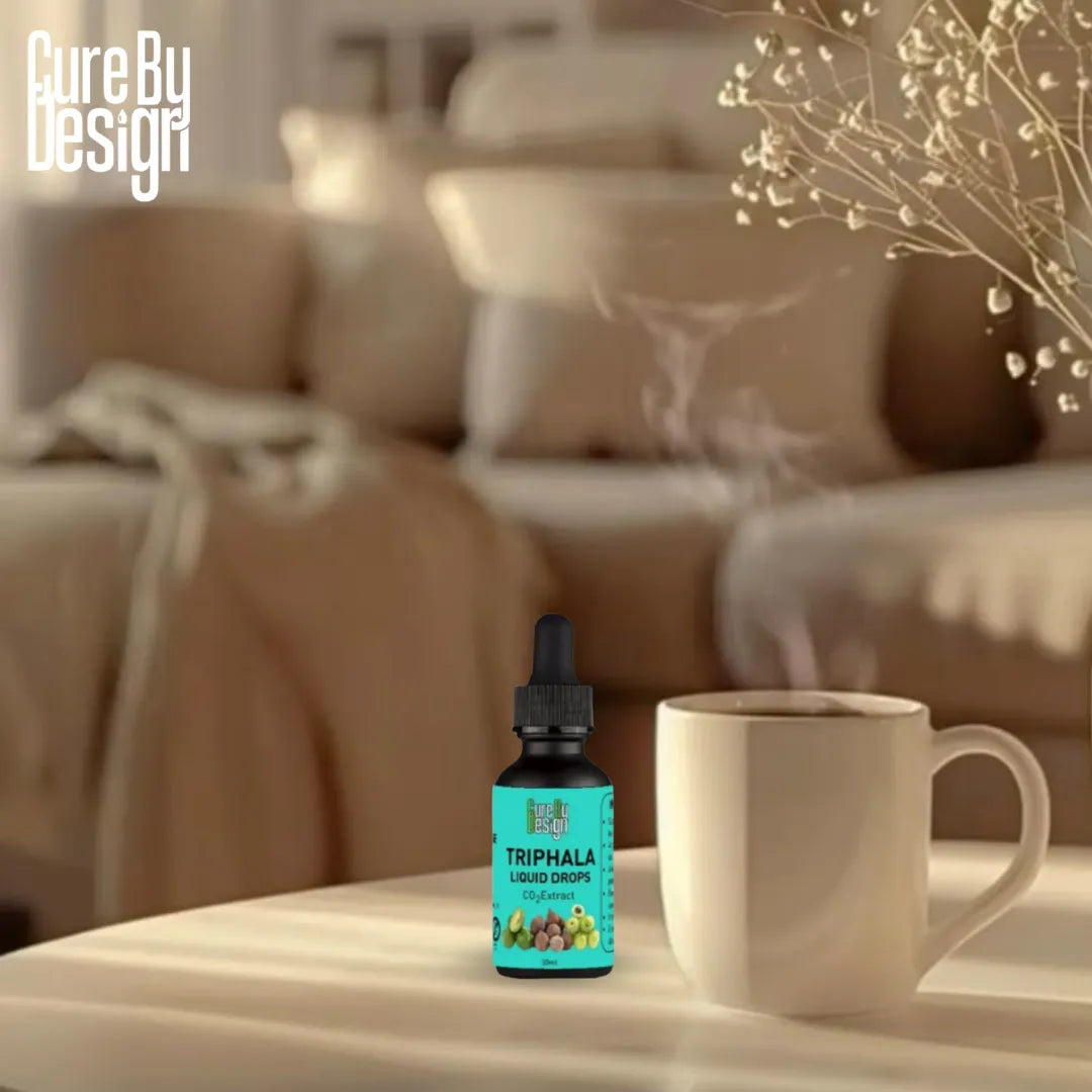 Cure By Design Triphala tincture bottle with a cup on a table in a cozy living room setting.