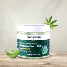 Load image into Gallery viewer, Jar of Cannarma Hemp Aloe Vera Gel on a wooden surface, with an aloe vera leaf and cannabis leaf nearby.
