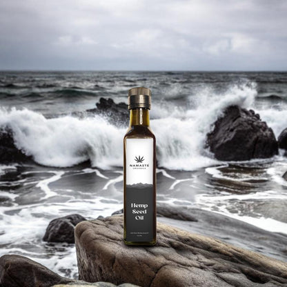Bottle of Namaste Naturals Hemp Seed Oil on a rock with ocean waves in the background