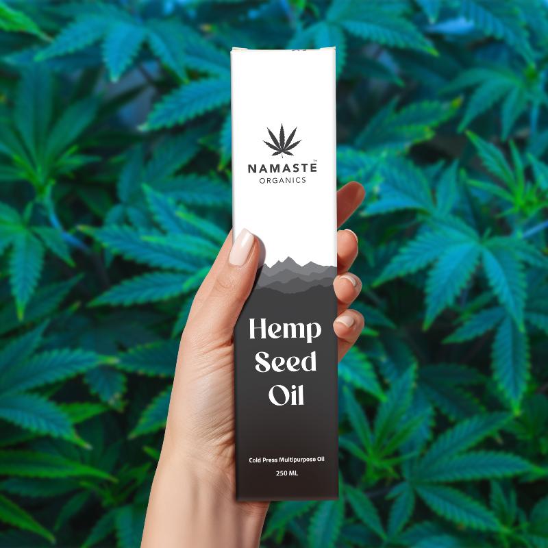Hand holding a bottle of Namaste Organics Hemp Seed Oil against a background of green leaves.