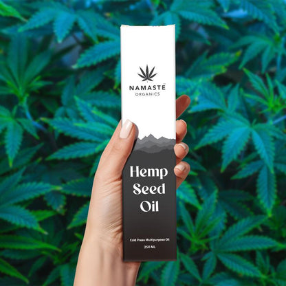 Hand holding a bottle of Namaste Organics Hemp Seed Oil against a background of green leaves.