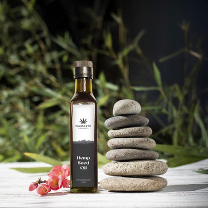 Bottle of Namaste Organics Hemp Seed Oil with stacked stones and flowers on a natural background