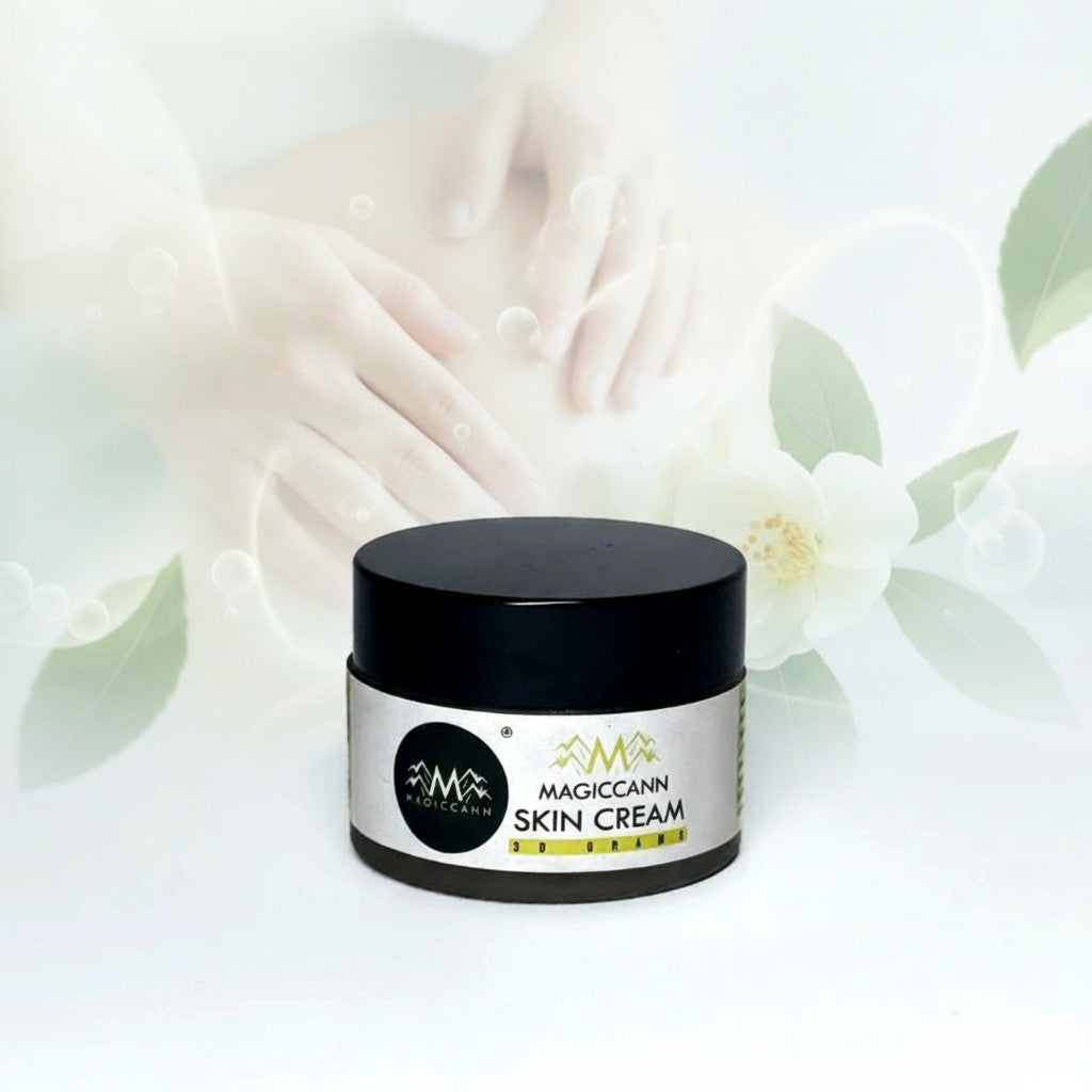 A jar of MAGICCANN Hemp Skin Cream with a black lid, set against a soft-focus background of hands, leaves, and flowers.
