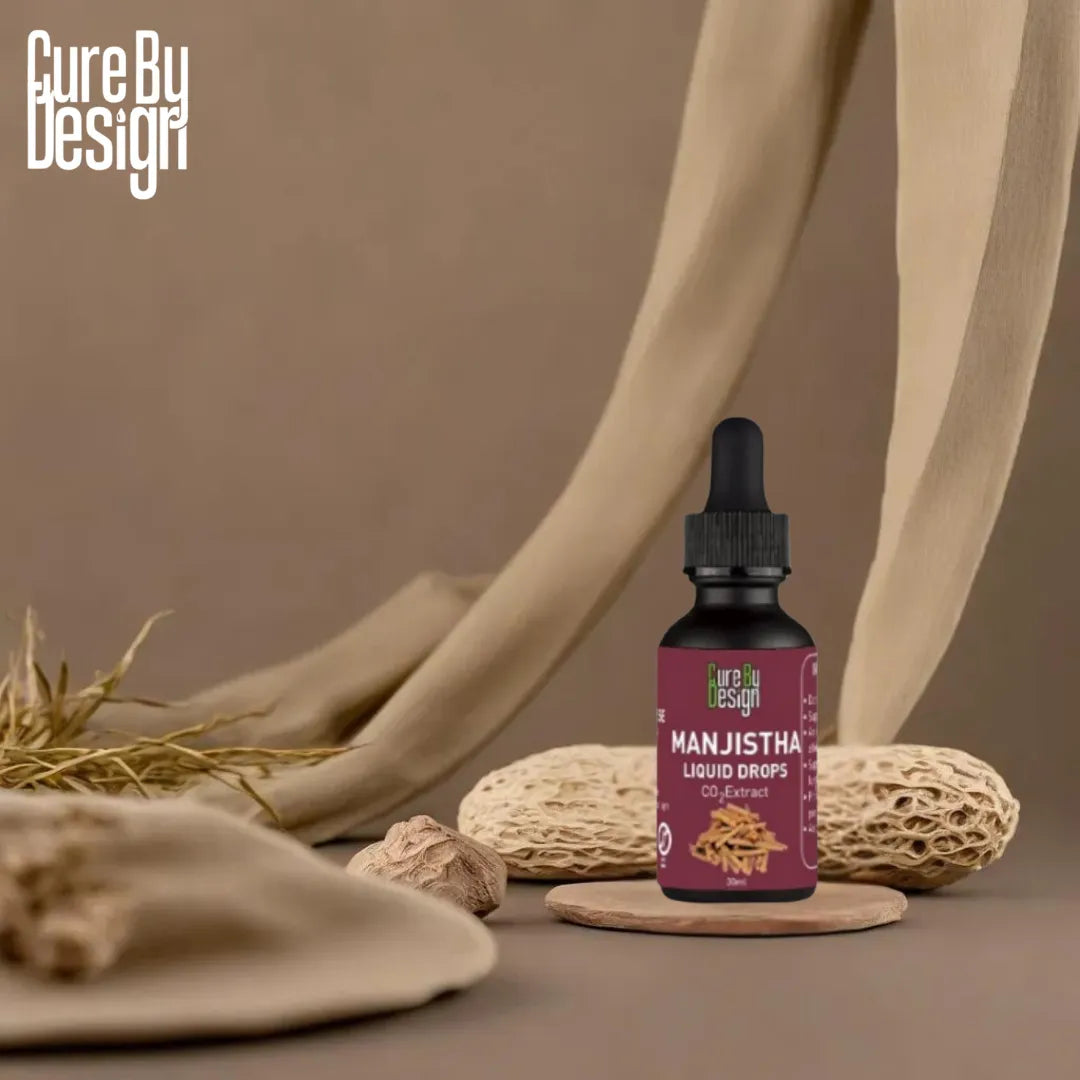 Manjistha liquid drops bottle with dropper on a brown background, featuring Cure By Design branding.