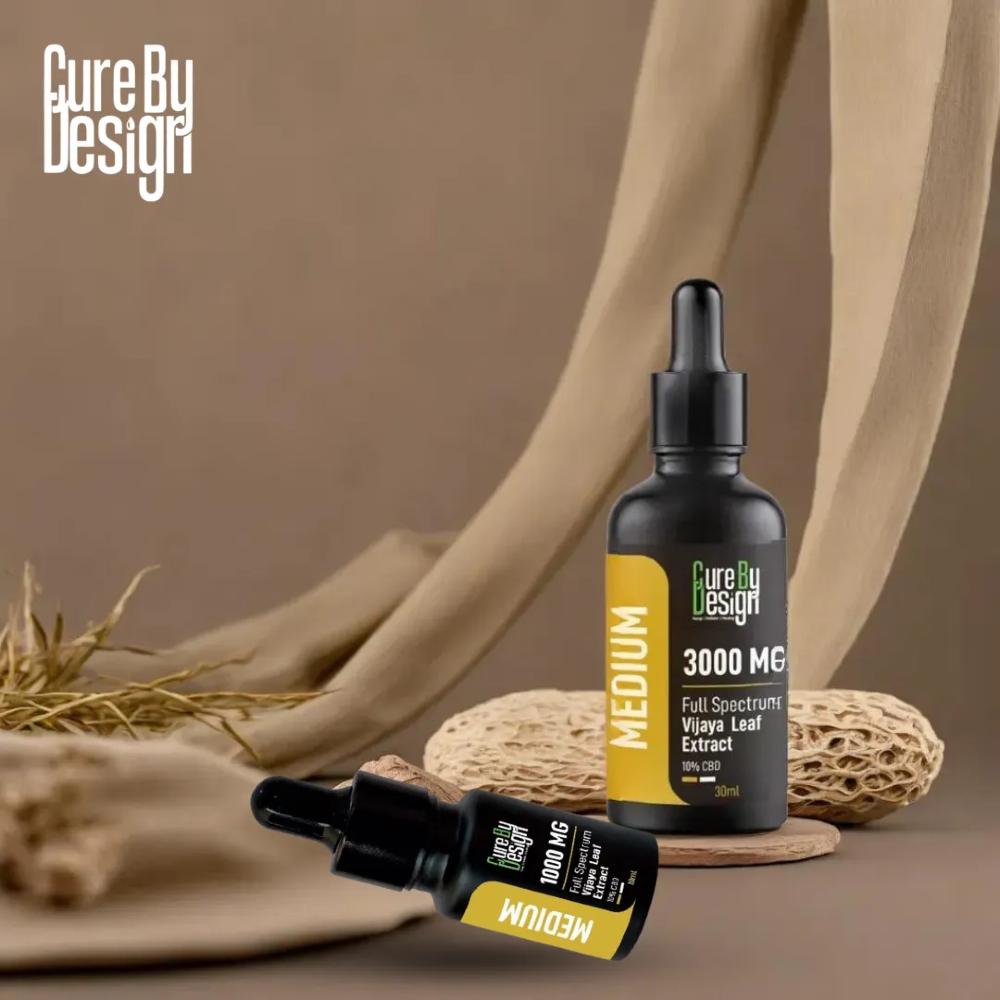 Two bottles of 'Cure By Design' full-spectrum vijaya leaf extract on a brown background with natural elements.