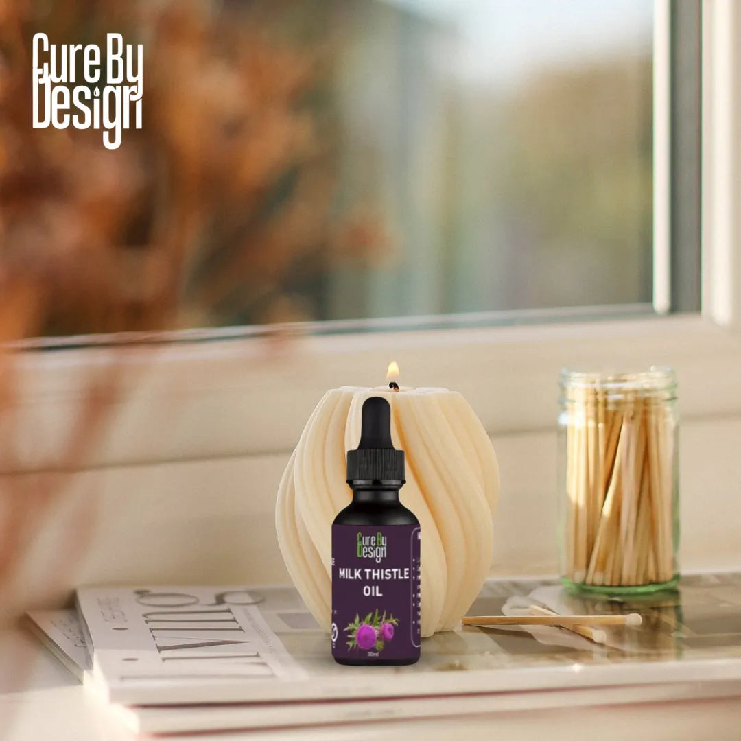 Bottle of Milk Thistle Oil with a candle and matches on a table, featuring Cure By Design branding.