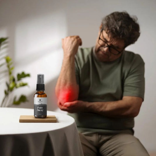 Man with a painful arm holding a bottle labeled 'Pain Away -  Full spectrum CBD Oil' on a table.