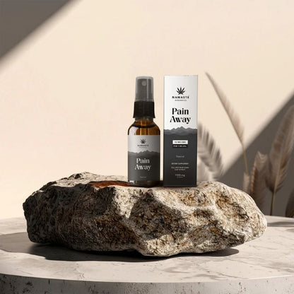 Namaste Naturals Pain Away Full spectrum CBD Oil spray bottle and packaging on a rock with a neutral background
