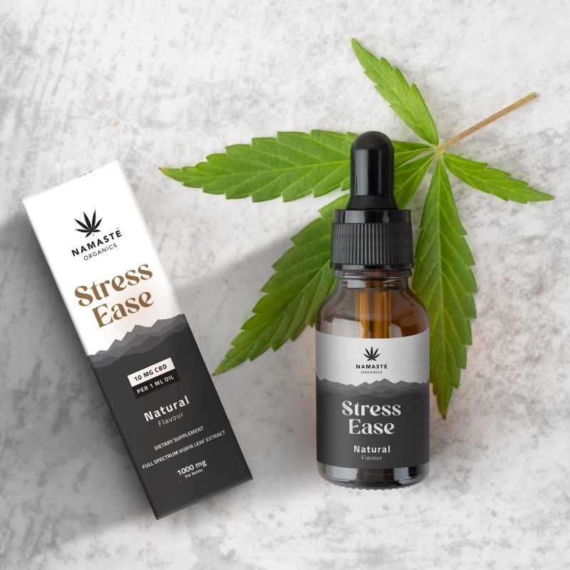 Namaste Organics Stress Ease Full spectrum CBD Oil product with bottle and packaging on a textured surface with leaves.
