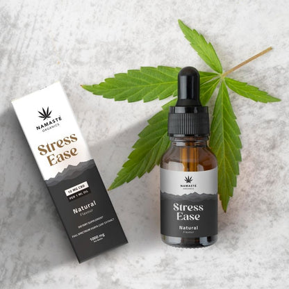 Namaste Organics Stress Ease Full spectrum CBD Oil product with bottle and packaging on a textured surface with leaves.