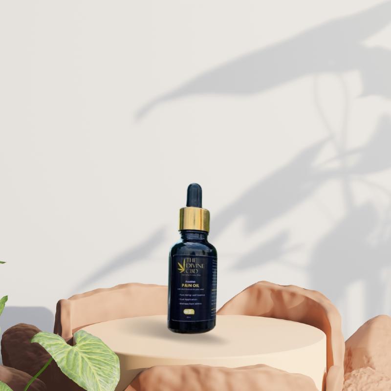 Dark glass bottle with gold cap on a circular pedestal with natural-looking rocks and green plants in the foreground.