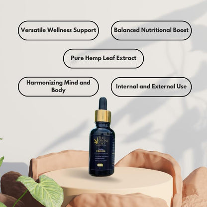  Dark blue bottle of Paarmi Cares' "The Divine CBD Pain Oil" on a circular stone podium with plant leaves.