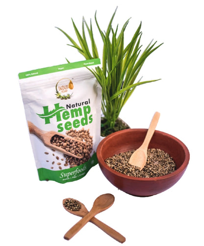 Hemp seeds packaging with a bowl of seeds, wooden spoons, and a plant on a white background
