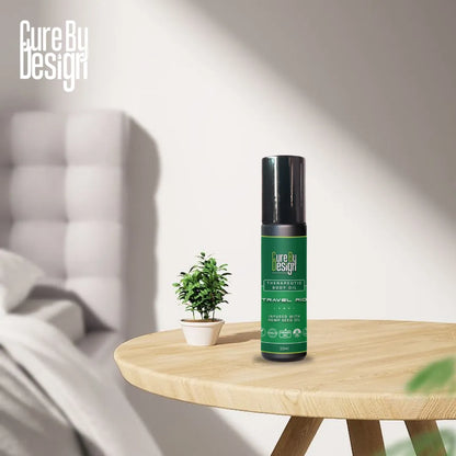 Green bottle with black cap on a wooden table, 'Cure by Design' branding visible