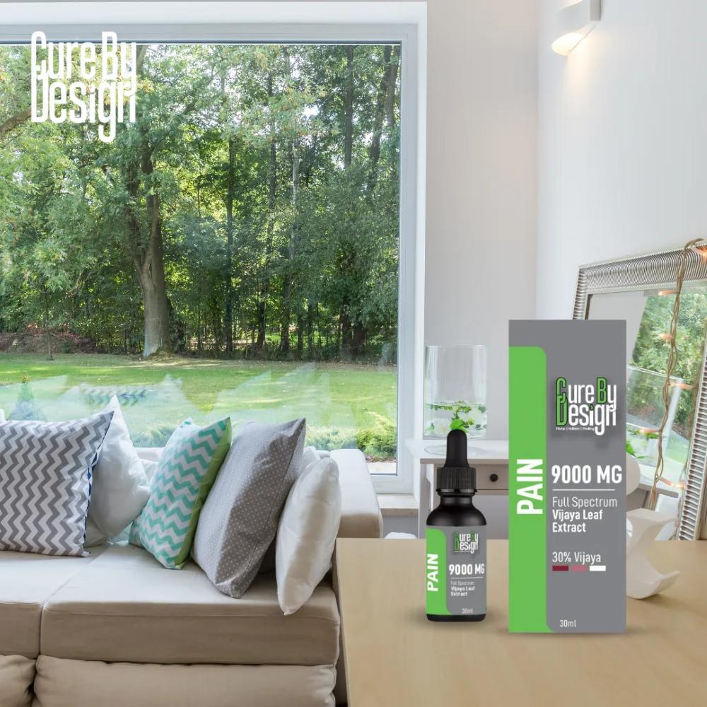 Product packaging for 'Cure By Design' CBD Oil Product on a coffee table in a modern living room with a view of trees.