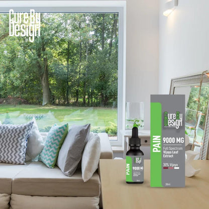 Product packaging for 'Cure By Design' CBD Oil Product on a coffee table in a modern living room with a view of trees.