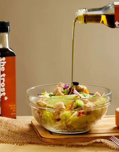 a bottle of hemp seed oil pouring on sald on top of a table