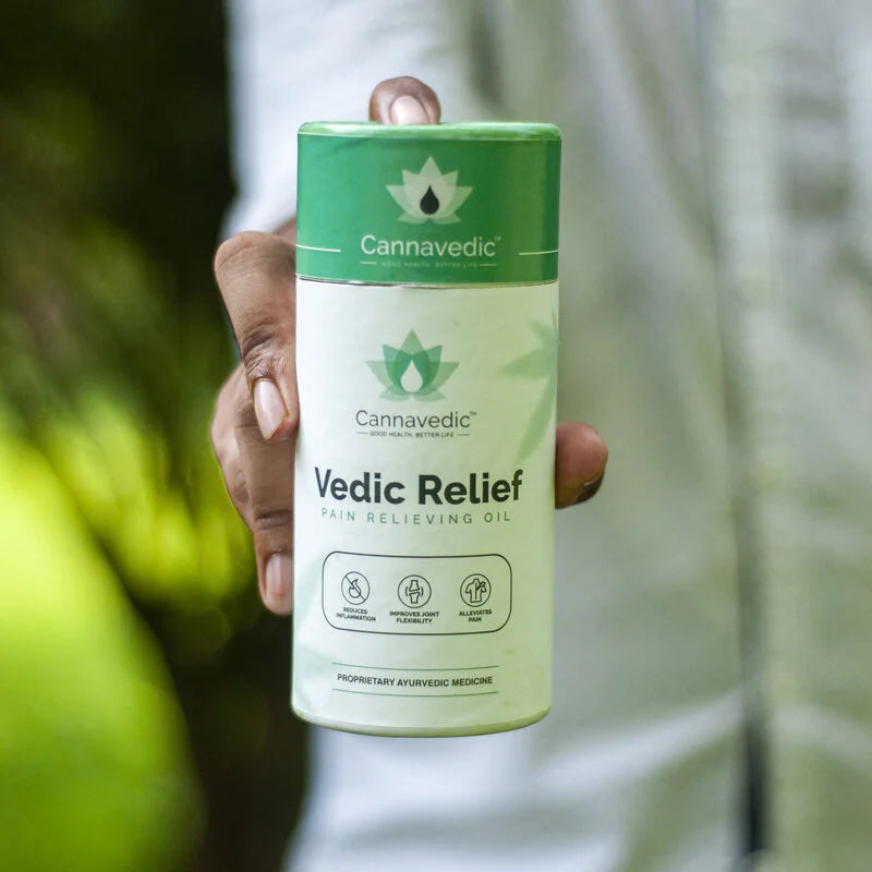 Hand holding a Cannavedic Vedic Relief Pain Relieving Oil container.