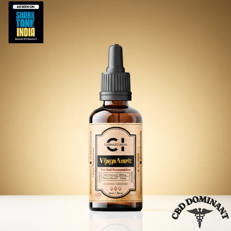 An amber glass dropper bottle of Cannazo Vijaya Amrit CBD tincture, set against a warm beige gradient background. The bottle has a black dropper cap and a beige label with black and gold text.