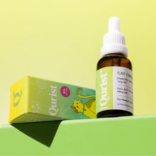 Load image into Gallery viewer, A bottle of cat CBD oil with a dropper cap next to a colorful box featuring a cat illustration.
