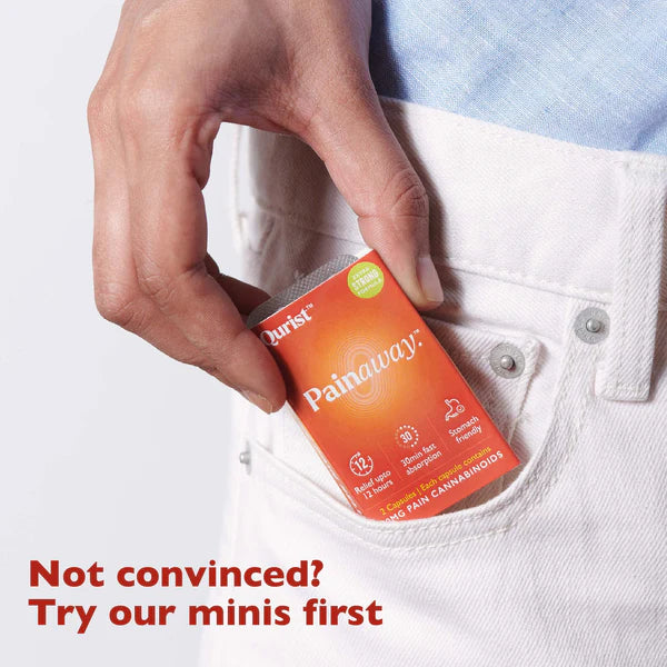 Hand placing an orange "Painaway" box into a white jeans pocket. 