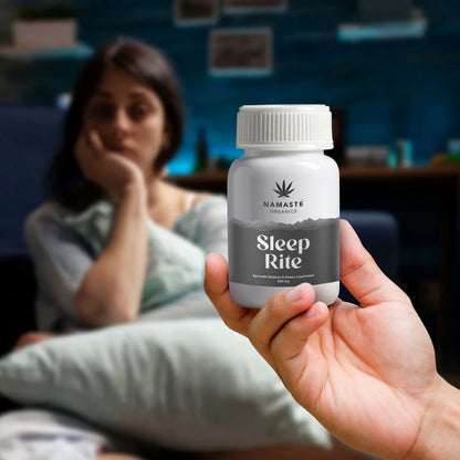 Hand holding a bottle labeled 'Sleep Rite' CBD Tablet by Namaste Organics in a blurred indoor setting.
