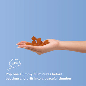 A hand holding orange-brown gummies on a light blue background.
